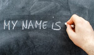 Teacher writing his name on blackboard